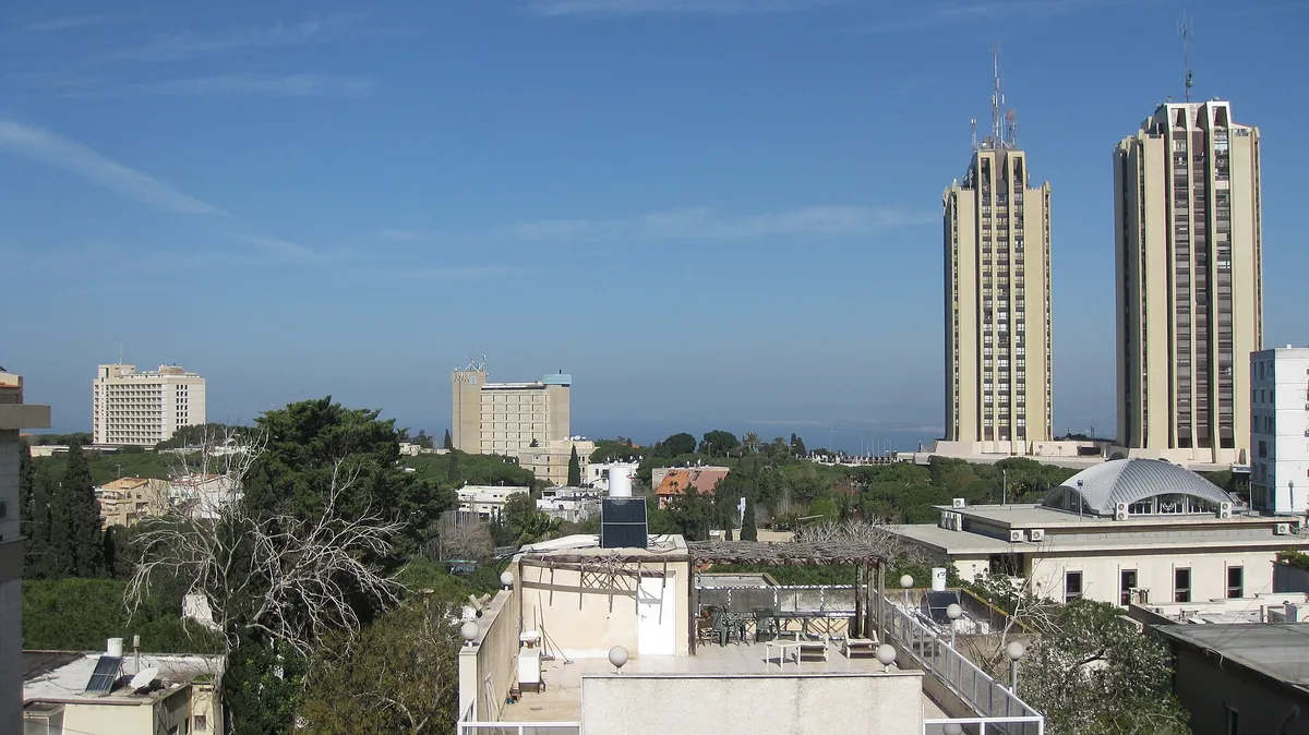 Carmel Center rooftops and pines with the twin Panorama towers and hotels on the ridge